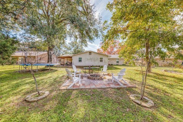 view of yard featuring an outdoor fire pit, a trampoline, and a patio area