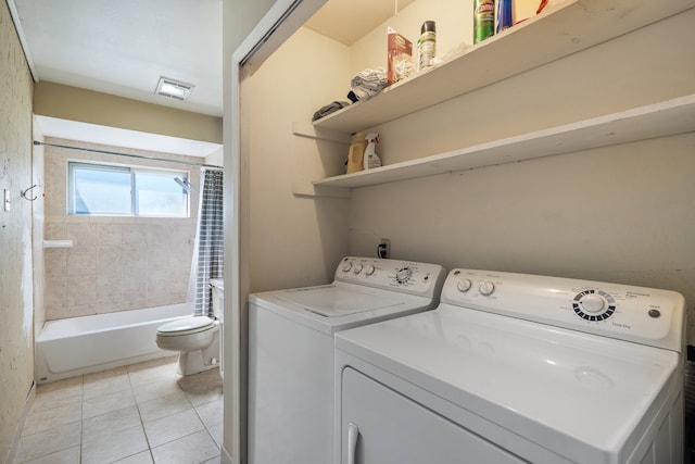 clothes washing area featuring light tile patterned floors and washer and dryer