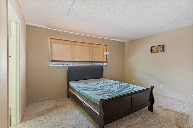 bedroom with light colored carpet and a textured ceiling