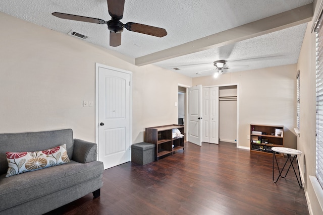 living area with beamed ceiling, ceiling fan, dark hardwood / wood-style floors, and a textured ceiling