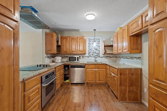 kitchen featuring light stone counters, hanging light fixtures, sink, stainless steel appliances, and dark hardwood / wood-style floors