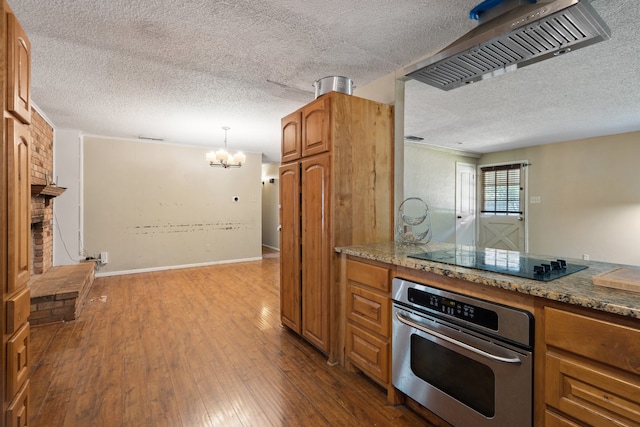 kitchen with pendant lighting, oven, black electric stovetop, hardwood / wood-style flooring, and a textured ceiling