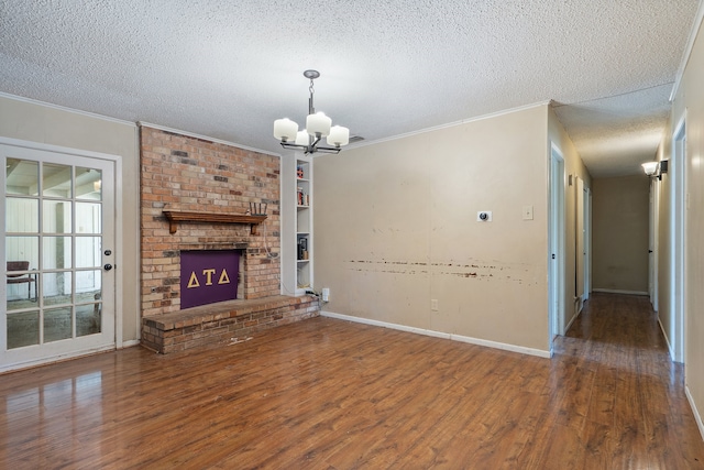 unfurnished living room with a brick fireplace, a chandelier, wood-type flooring, crown molding, and a textured ceiling