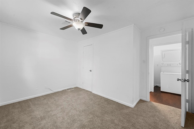 carpeted spare room with stacked washer / drying machine and ceiling fan