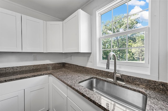 kitchen with sink, white cabinetry, and dark stone counters