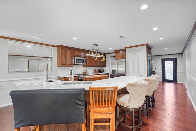 kitchen featuring appliances with stainless steel finishes, ornamental molding, dark wood-type flooring, pendant lighting, and a kitchen island