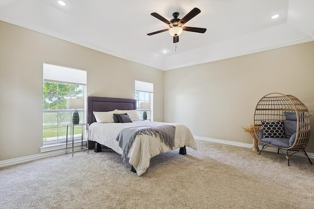 carpeted bedroom featuring a raised ceiling, crown molding, multiple windows, and ceiling fan