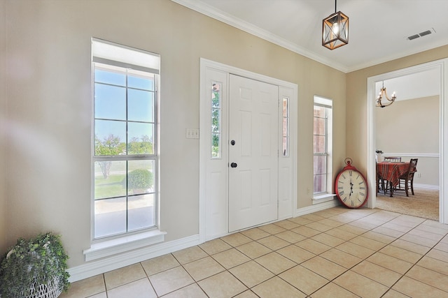 tiled foyer featuring crown molding and a chandelier