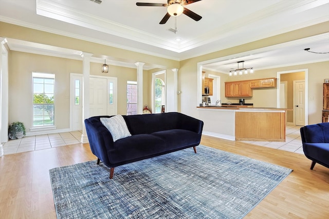 living room with ceiling fan, light wood-type flooring, crown molding, and decorative columns