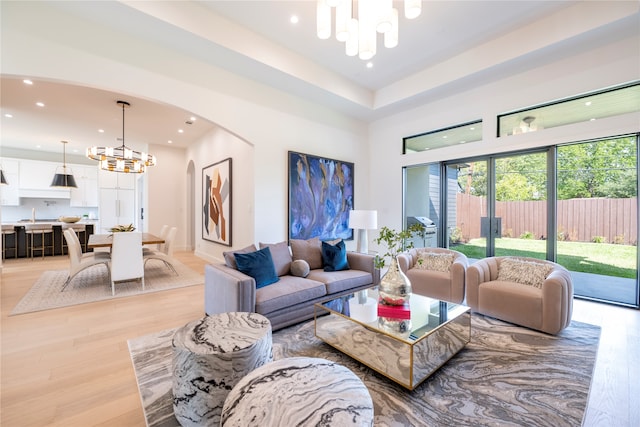 living room with a notable chandelier, light hardwood / wood-style floors, and sink