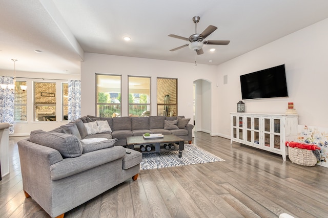 living room with dark wood-type flooring and ceiling fan with notable chandelier