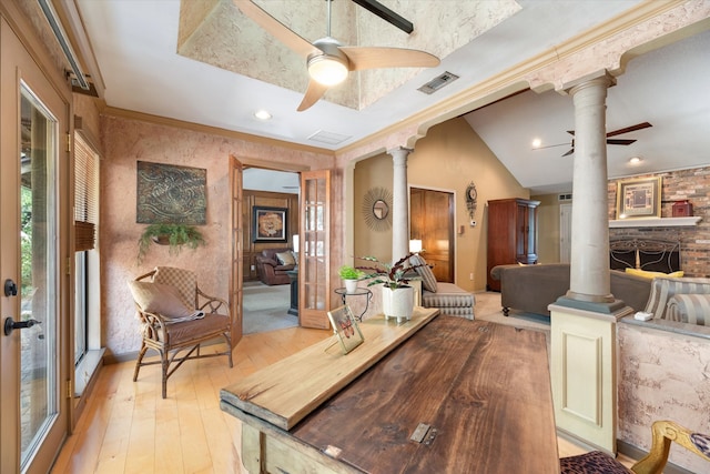 dining space with light wood-type flooring, ceiling fan, a large fireplace, decorative columns, and lofted ceiling