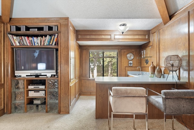 carpeted office space featuring beamed ceiling, a textured ceiling, wood walls, and sink