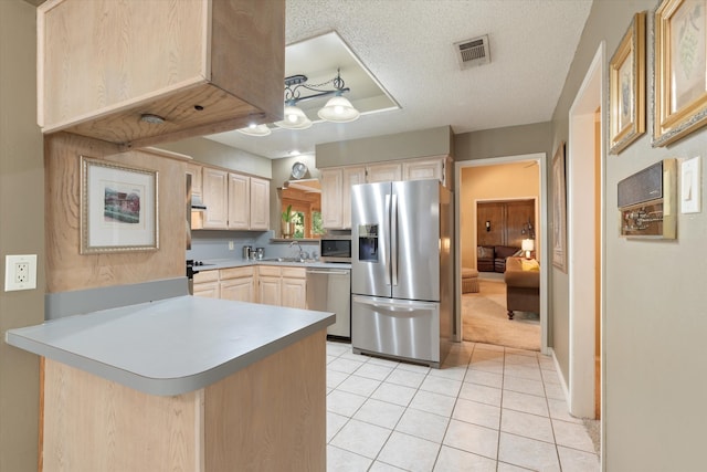 kitchen with sink, kitchen peninsula, a textured ceiling, appliances with stainless steel finishes, and light brown cabinetry