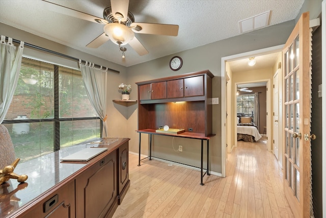 kitchen with ceiling fan, light hardwood / wood-style floors, a textured ceiling, and a healthy amount of sunlight