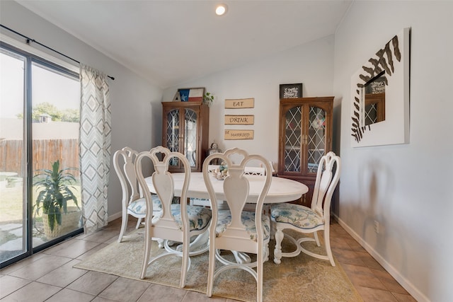 dining space with light tile patterned flooring and vaulted ceiling