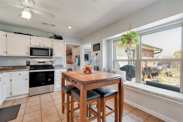 kitchen with separate washer and dryer, white cabinets, stainless steel appliances, ceiling fan, and light tile patterned floors