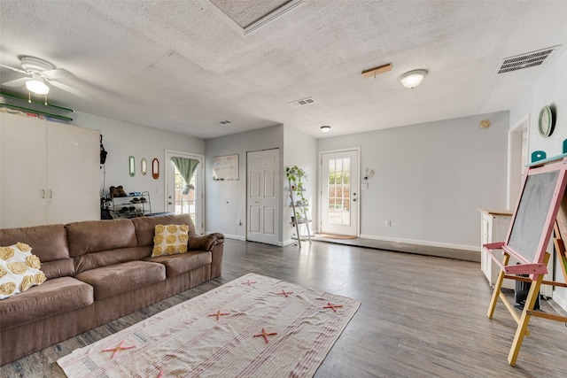 living room featuring ceiling fan, hardwood / wood-style floors, and a textured ceiling