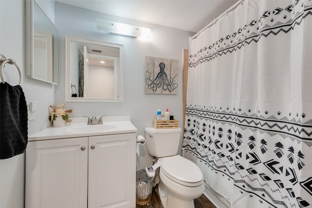 bathroom with curtained shower, a textured ceiling, toilet, and vanity