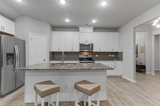 kitchen featuring a kitchen island with sink, sink, white cabinets, and appliances with stainless steel finishes