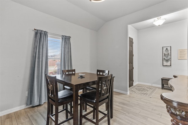 dining area with light wood-type flooring and lofted ceiling