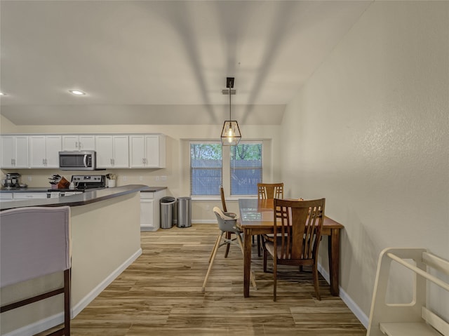 kitchen featuring pendant lighting, light wood-type flooring, stainless steel appliances, and white cabinets