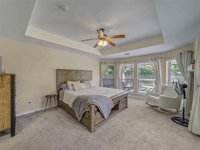 carpeted bedroom featuring ceiling fan and a raised ceiling