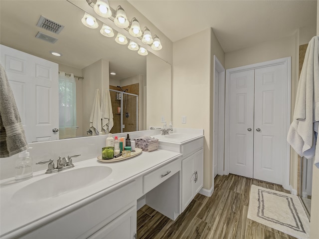 bathroom with walk in shower, vanity, and hardwood / wood-style flooring