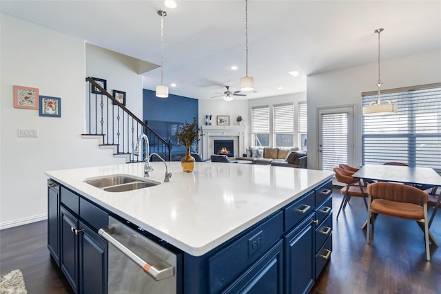 kitchen featuring blue cabinetry, sink, stainless steel dishwasher, and a center island with sink