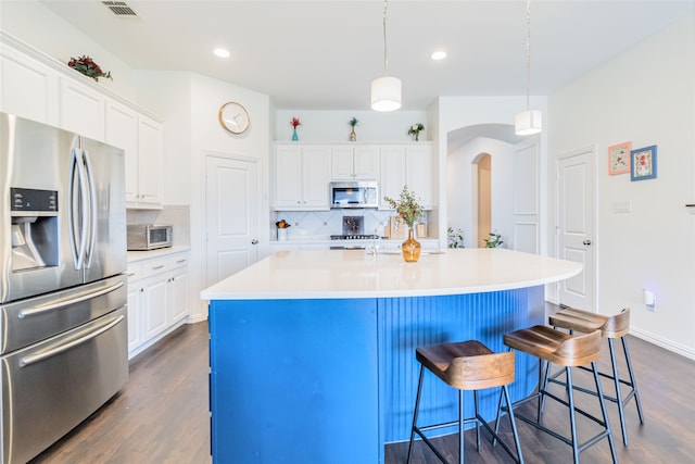 kitchen featuring white cabinets, stainless steel appliances, and an island with sink