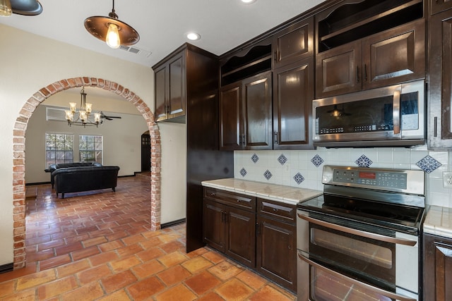 kitchen with stainless steel appliances, tasteful backsplash, dark brown cabinetry, and pendant lighting