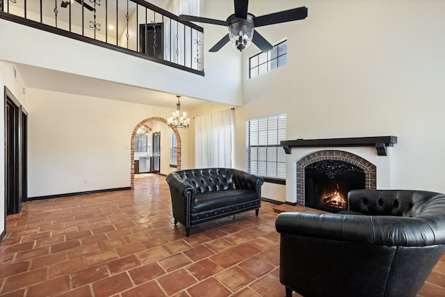 living room with ceiling fan with notable chandelier and a high ceiling