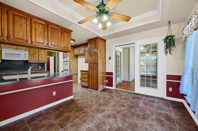 kitchen with tasteful backsplash, white appliances, dark stone countertops, sink, and light tile patterned floors