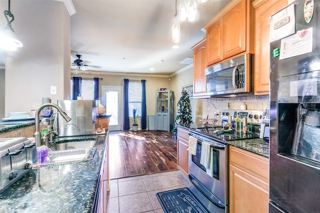 kitchen featuring stainless steel appliances, pendant lighting, dark stone counters, crown molding, and light hardwood / wood-style flooring