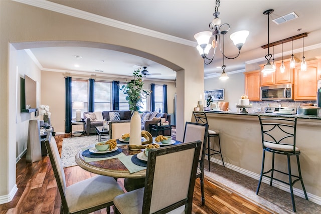 dining room featuring ceiling fan with notable chandelier, crown molding, and dark hardwood / wood-style floors