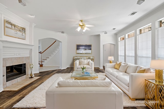 living room featuring ceiling fan, a fireplace, dark hardwood / wood-style floors, and crown molding