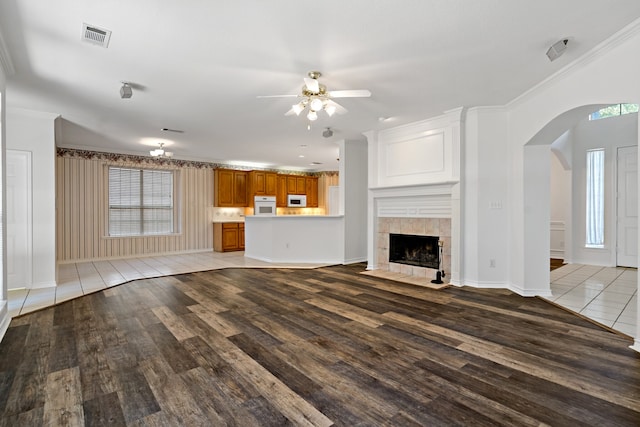 unfurnished living room with ceiling fan, light wood-type flooring, crown molding, and a fireplace