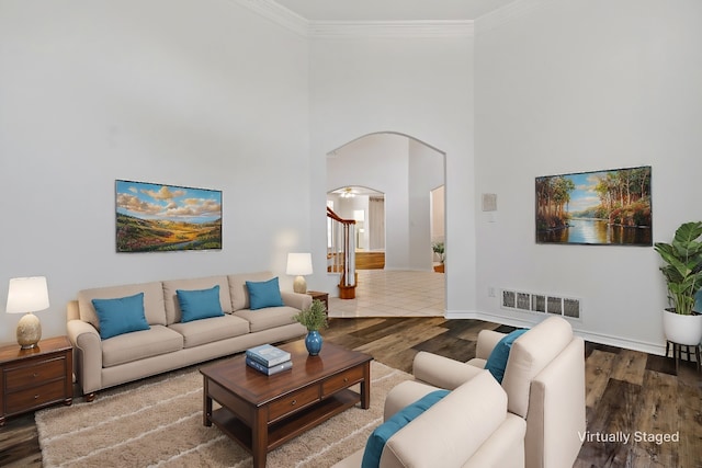 living room featuring crown molding, a towering ceiling, and wood-type flooring