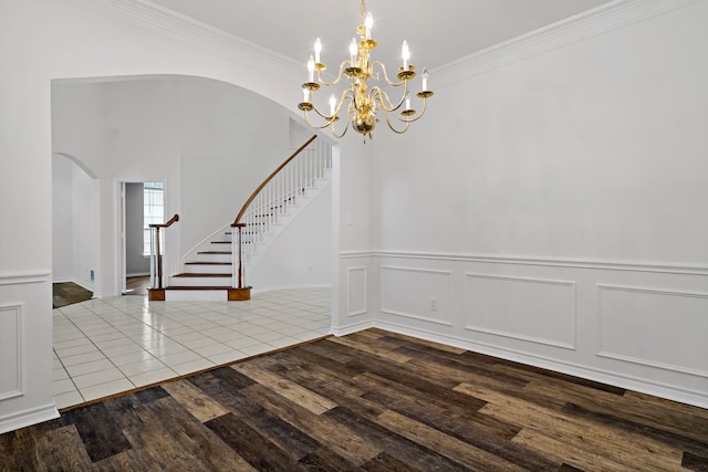 unfurnished dining area featuring crown molding, a chandelier, and wood-type flooring