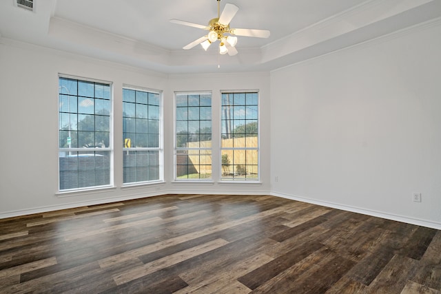 spare room featuring a raised ceiling, ornamental molding, dark hardwood / wood-style flooring, and a wealth of natural light