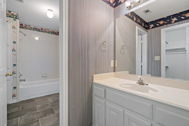 bathroom with tiled shower / bath combo, tile patterned floors, vanity, and a textured ceiling