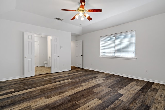 unfurnished bedroom with ceiling fan, connected bathroom, and dark hardwood / wood-style flooring