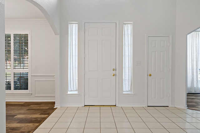 entryway with ornamental molding and light wood-type flooring