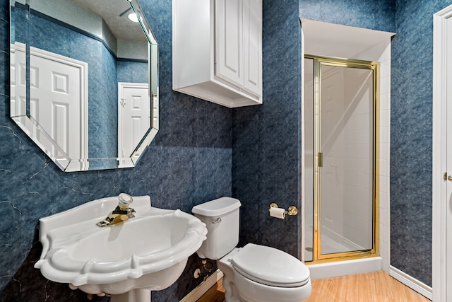 bathroom with toilet, sink, hardwood / wood-style floors, and a shower with door