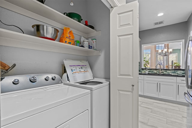 laundry room featuring independent washer and dryer, sink, a chandelier, and light hardwood / wood-style flooring