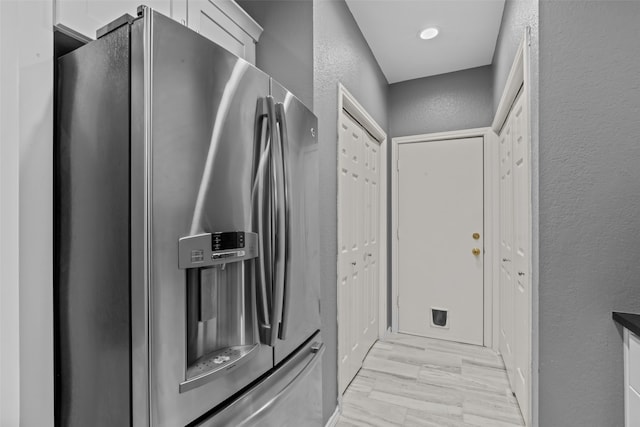 kitchen featuring light hardwood / wood-style floors, stainless steel fridge with ice dispenser, and white cabinetry