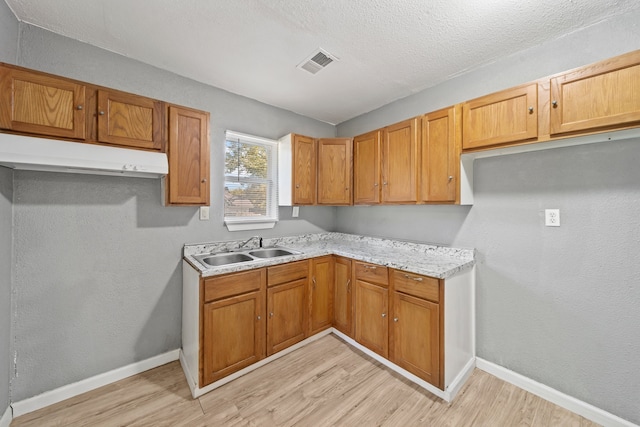 kitchen featuring sink, light hardwood / wood-style flooring, and a textured ceiling