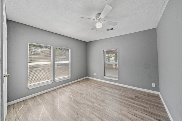 spare room with a textured ceiling, light wood-type flooring, and ceiling fan