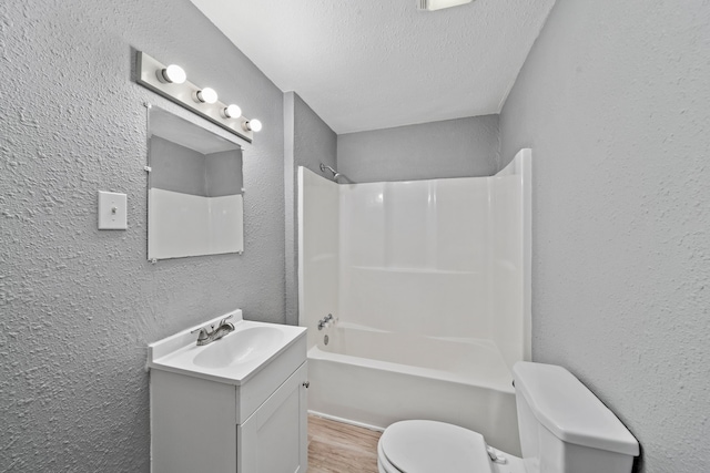 full bathroom with toilet, shower / washtub combination, hardwood / wood-style floors, vanity, and a textured ceiling