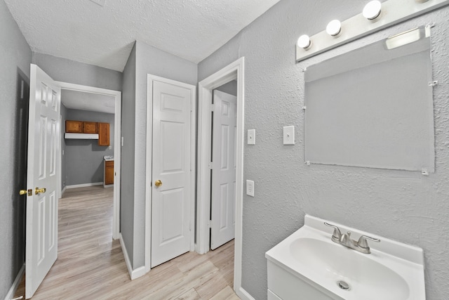 bathroom featuring vanity, wood-type flooring, and a textured ceiling